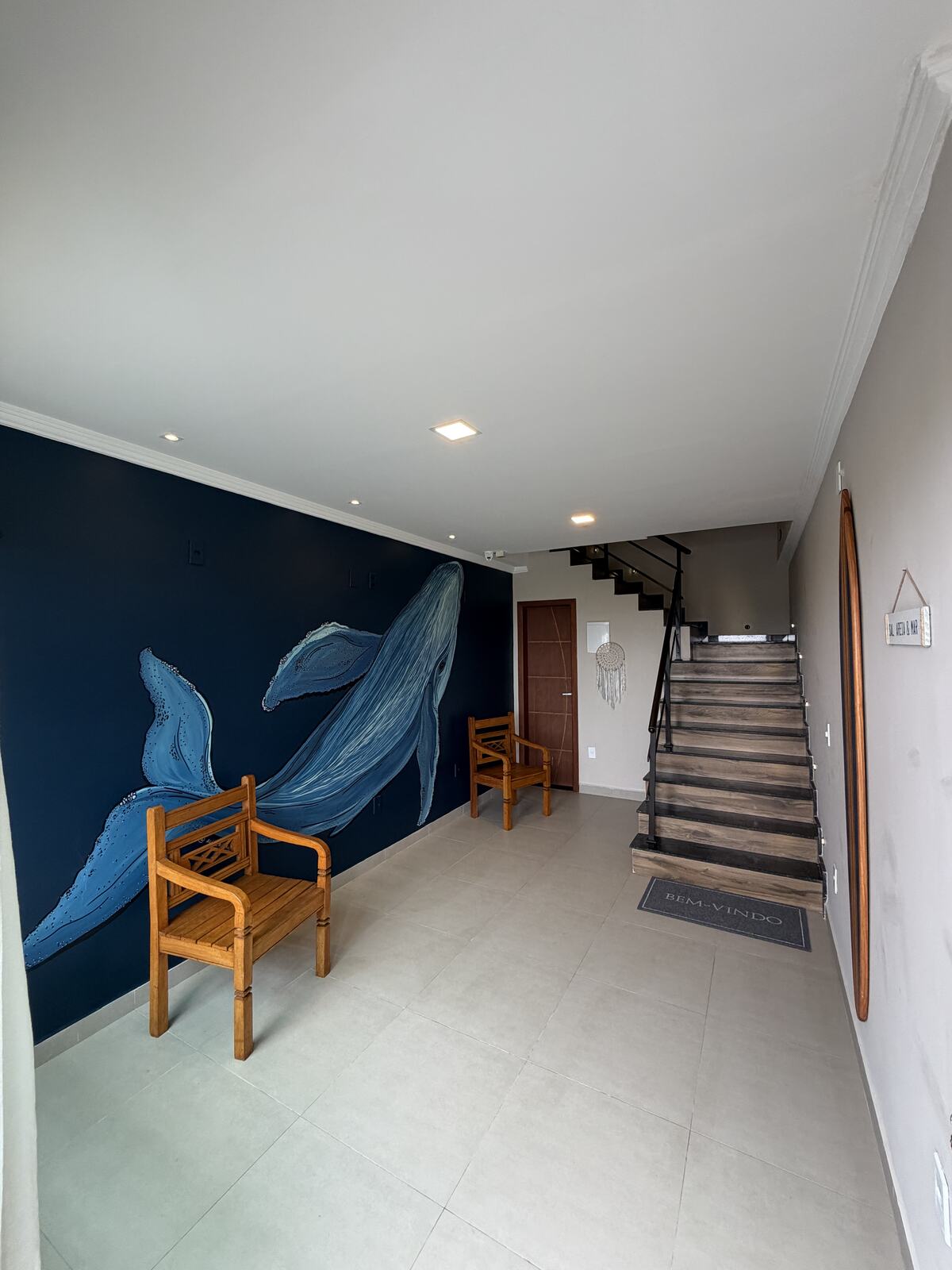 Recepção dos Éolos Lofts com mural de baleia e acesso ao andar superior